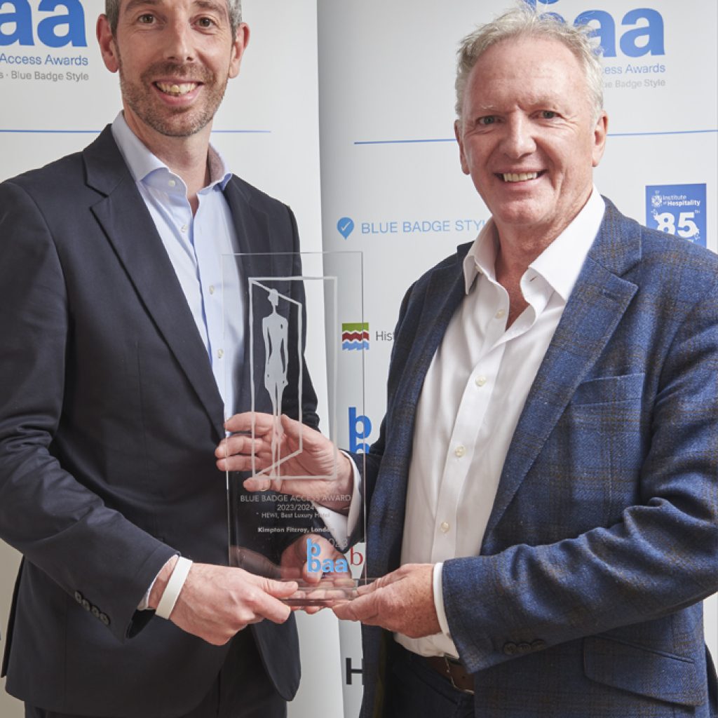 two grey haired men in dark blue jackets holding glass award 